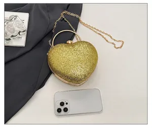 Heart-shaped gold glitter evening bag compared with a smartphone for size reference.