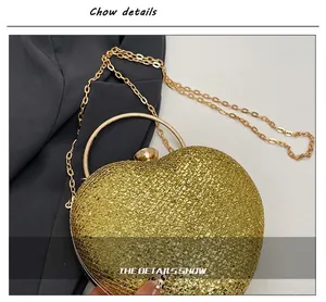 Detailed view of a heart-shaped gold glitter evening clutch bag with chain strap