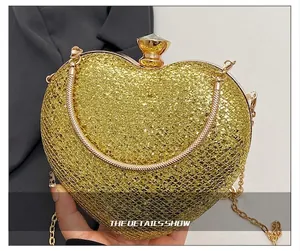 Detail of gold glitter heart-shaped clutch bag with elegant metal handle and chain