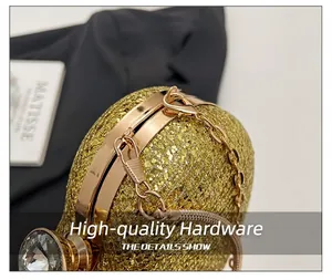 Close-up of golden glitter heart-shaped evening bag with metallic chain and crystal.