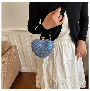 Model holding blue heart-shaped evening bag with sparkling rhinestones and gold handle