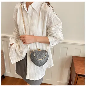 Model wearing a stylish heart-shaped crossbody evening bag with a gold chain strap.