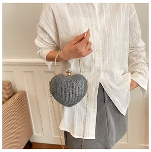 Lifestyle view of a glittery heart-shaped evening bag with gold metal chain strap
