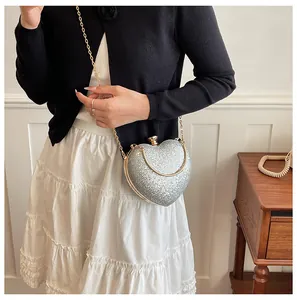 Close-up of elegant silver glitter heart-shaped evening clutch bag with a gold chain strap