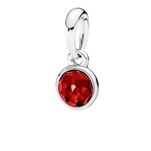Close-up of silver-plated charm pendant featuring a vibrant round faceted red birthstone
