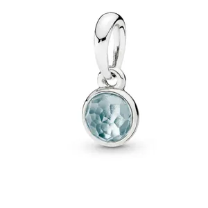 Close-up of silver-plated charm pendant featuring a faceted light blue birthstone
