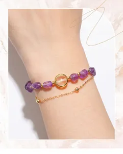 Close-up detail of a double-layered natural amethyst bead and gold chain bracelet on wrist