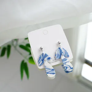 Close-up detail of blue and white ceramic dangle earrings featuring 925 silver posts