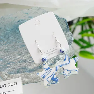 Close-up of star-shaped blue and white porcelain earrings with 925 silver hooks