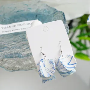 Detailed macro view of blue and white ceramic earrings with 925 silver hooks for women