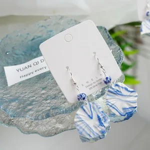 Close-up of blue and white ceramic earrings with 925 silver posts on a display card.