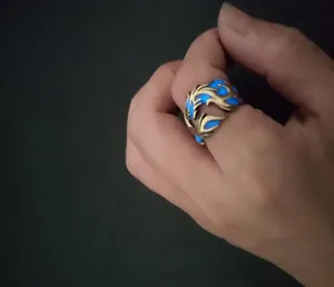 Detailed close-up of a luminous dragon pattern wide band ring glowing blue in the dark