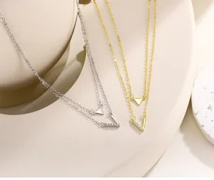 Close-up of double-layer S925 silver and gold necklaces with geometric V and triangle pendants