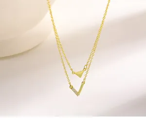 Elegant close-up of double-layered gold necklace with V and triangle shaped pendants