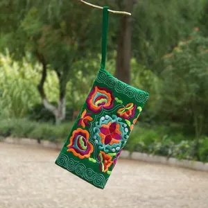 Close-up of a green Yunnan ethnic style embroidered floral canvas coin purse hanging outdoors