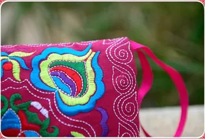 Macro detail shot of colorful ethnic floral embroidery on a fuchsia canvas coin purse