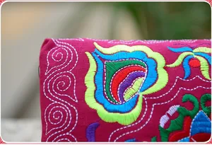 Detailed view of colorful ethnic floral embroidery on a vibrant rose pink canvas purse