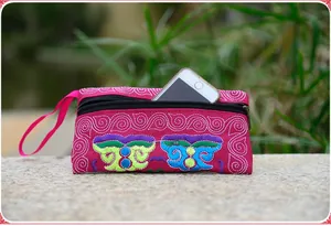 Close-up of a vibrant pink ethnic embroidered canvas clutch bag holding a smartphone.