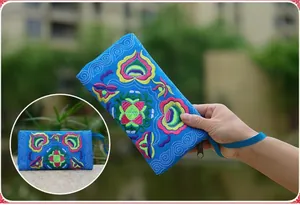 Detailed view of the vibrant sky blue ethnic floral embroidery on a canvas long wallet