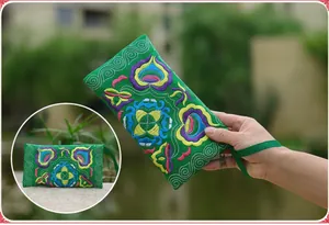 Close-up detailed view of vibrant Miao embroidery on this green canvas phone clutch bag