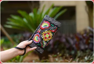 Detailed view of traditional Miao floral embroidery on a black canvas phone pouch