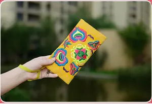 Detailed view of the yellow canvas phone bag featuring vibrant ethnic Miao floral embroidery