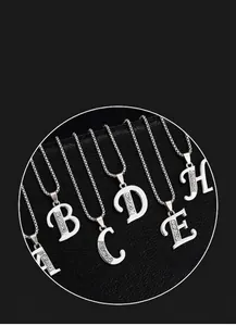 Vue rapprochée de colliers avec initiales argentées et strass étincelants sur fond noir.