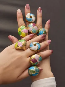 Close-up of multiple colorful enamel floral rings with zircons on model's fingers.