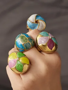 Close-up of colorful enamel flower rings with cubic zirconia inlay on a hand detail