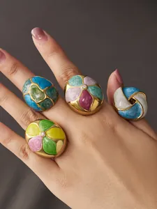 Detailed view of colorful enamel floral rings with zircon stones on a model hand.