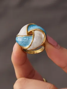 Close-up detail of a vintage stainless steel ring with blue and white enamel design