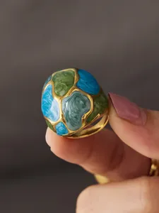 Close-up detail of a vintage stainless steel ring with blue and green enamel patterns.
