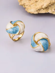 Close-up of elegant blue and white enamel flower rings featuring a polished golden finish