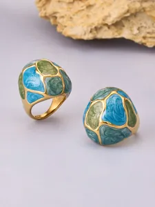 Close-up of retro stainless steel rings with colorful blue and green enamel petal design.