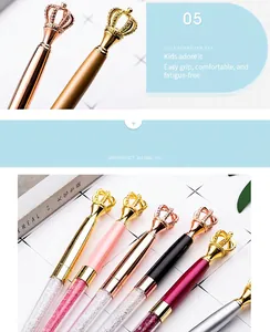 Close-up of elegant metal crown toppers on various colored crystal ballpoint pens
