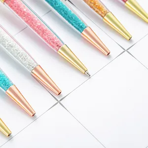 Elegant metal ballpoint pens filled with colorful sparkling crystals on white grid paper
