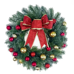 Couronne de Noël verte décorée d'un nœud rouge et d'ornements dorés et rouges.