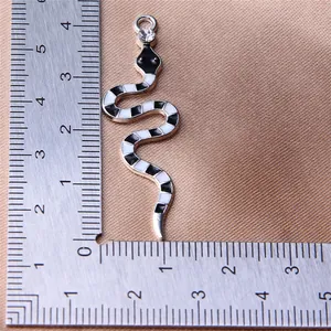 Macro view of black and white enamel snake pendant showing detailed size with ruler.