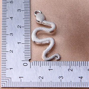 Detailed close-up of a silver snake pendant charm with a scale ruler for size reference