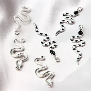 Close-up detail of silver snake charms with black and white enamel patterns for DIY jewelry