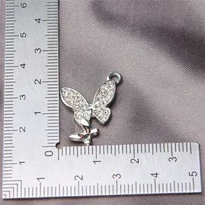 Exquisite silver butterfly charm with sparkling rhinestones measured by a metal ruler