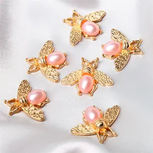 Detailed view of six golden alloy bee charms featuring pink pearl bodies on silver satin