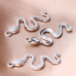 Detailed close-up view of silver-tone snake pendants for DIY jewelry making on silk