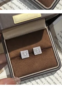 Detailed close-up of elegant square zircon stud earrings in a luxury brown jewelry box