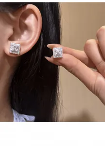 Close-up detail of elegant square cubic zirconia stud earrings shown on ear and hand