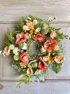 Detailed view of artificial spring wreath with poppies and berries on a wooden door