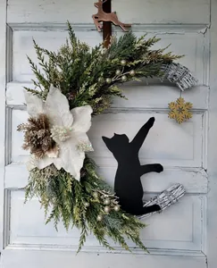 Detailed view of moon-shaped Christmas wreath with white flower and black cat silhouette