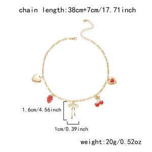 Detail view of gold charm necklace with cherry and strawberry pendants showing measurements