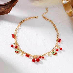 Sweet gold chain necklace featuring red cherry pendants and heart charms on white texture