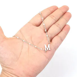 Detailed shot of a silver M alphabet necklace with elegant faux pearl accents on hand